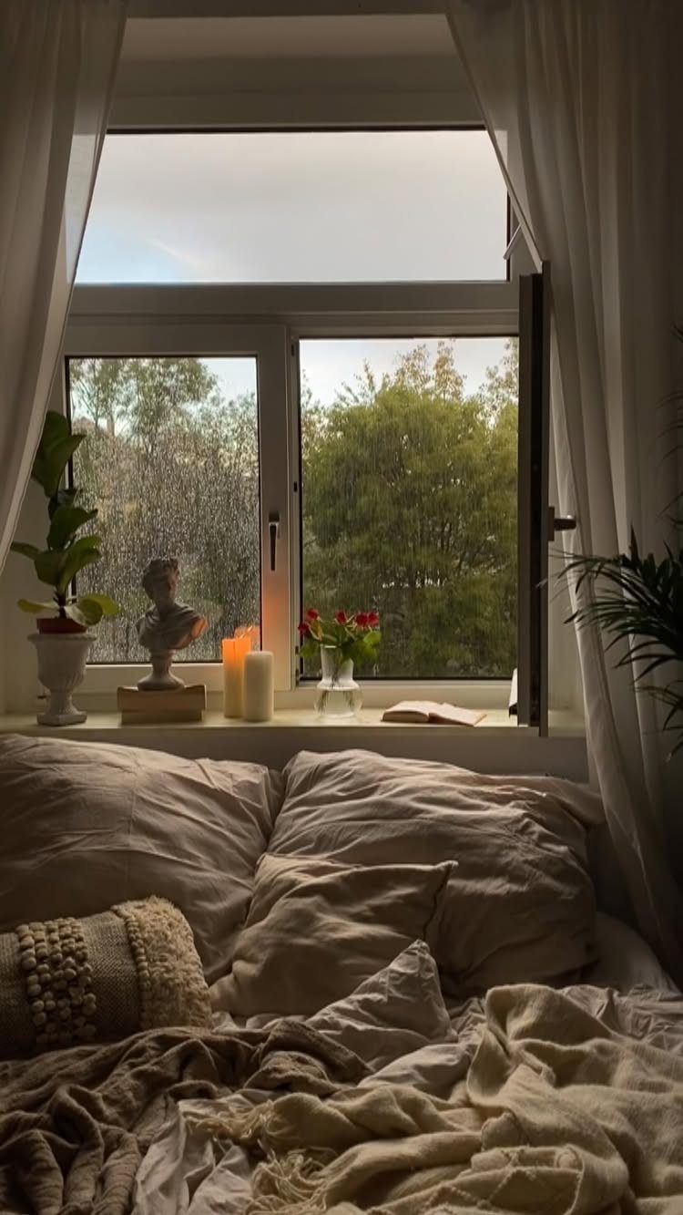 Cozy bedroom with lit candles and a classical bust on a window sill.