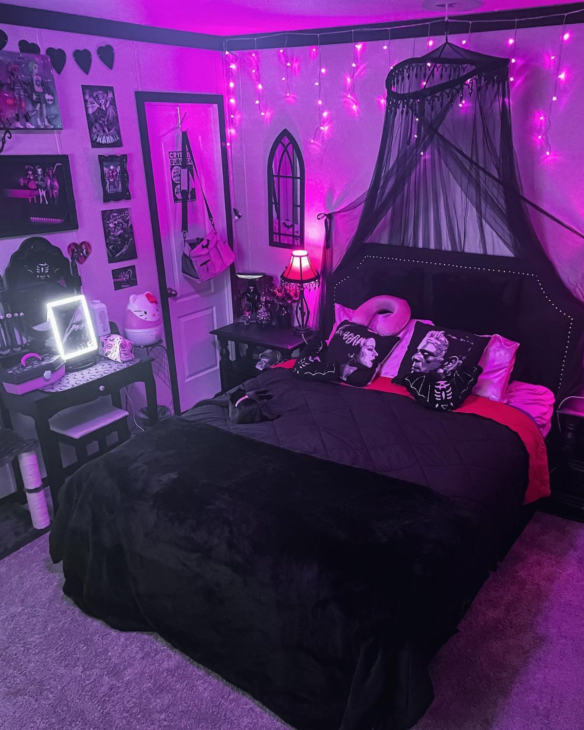 Bedroom with black bed, canopy netting, and pink LED lighting with gothic decor.
