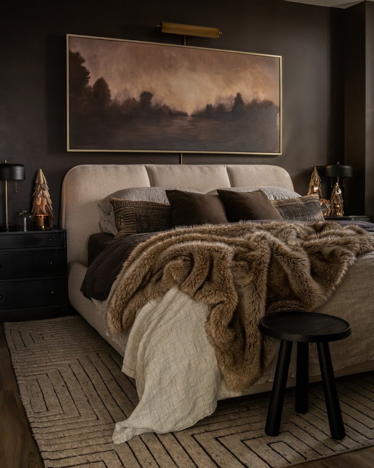 Bed with layered faux-fur and knit blankets in a dark brown bedroom
