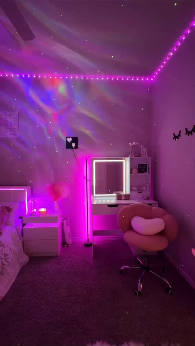 Bedroom with pink LED strip lights along the ceiling and a pink vanity chair.