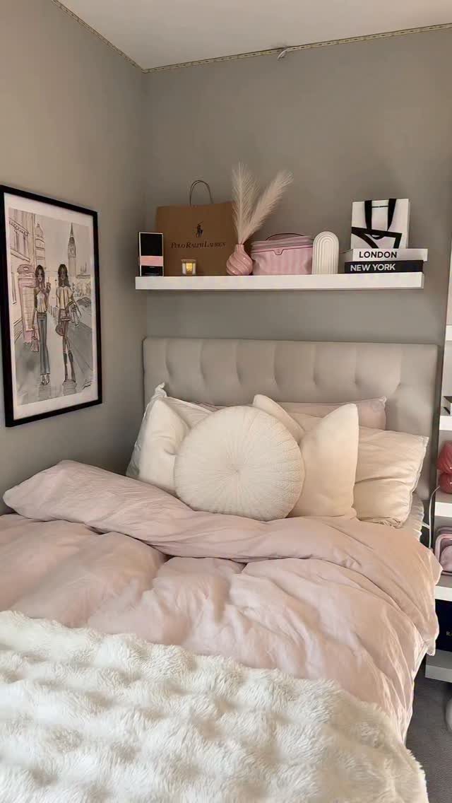 Pink bedding and white fluffy throw in a bedroom with a floating shelf.