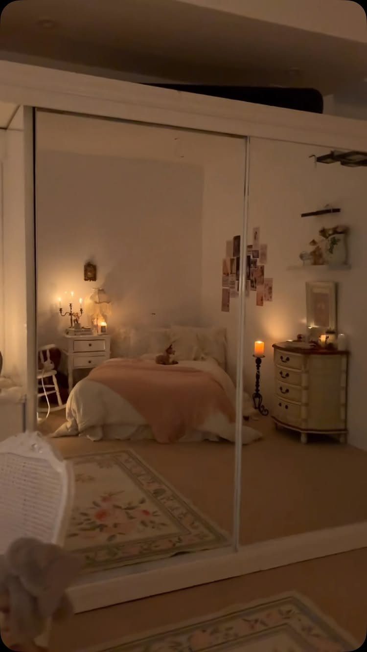 Bedroom with vintage white dresser, floral rug, and warm lighting reflected in a mirror.