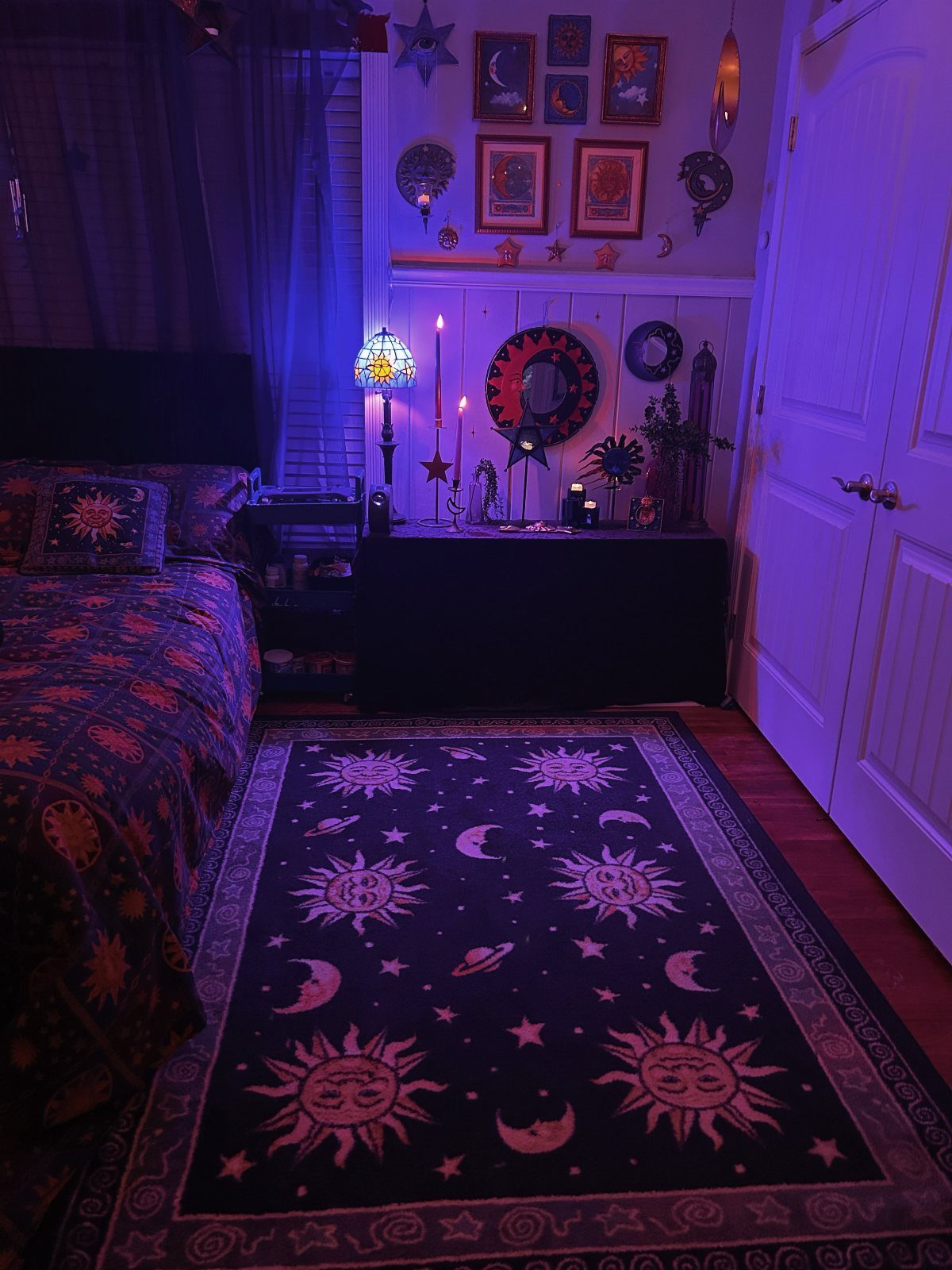 Witchcore bedroom with purple lighting, celestial patterned rug, and occult wall decor.