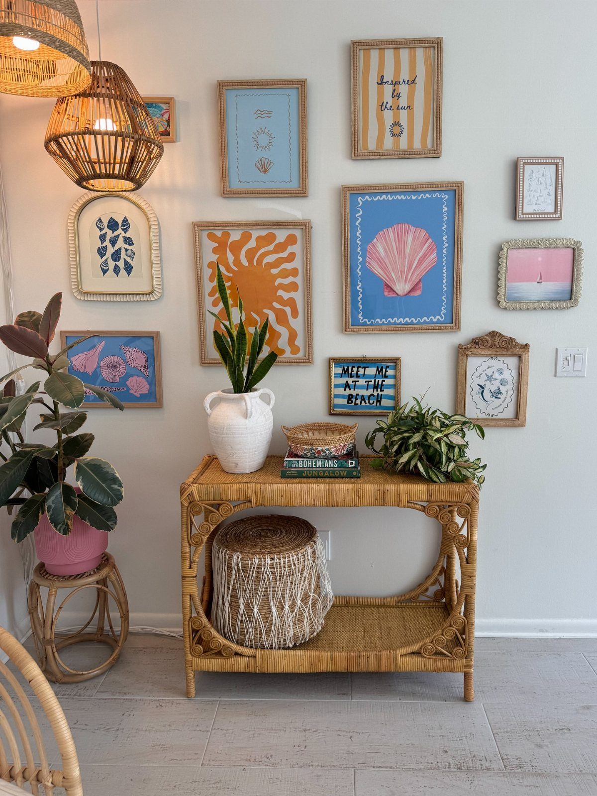 Wicker console table and gallery wall with coastal art and woven pendant lights