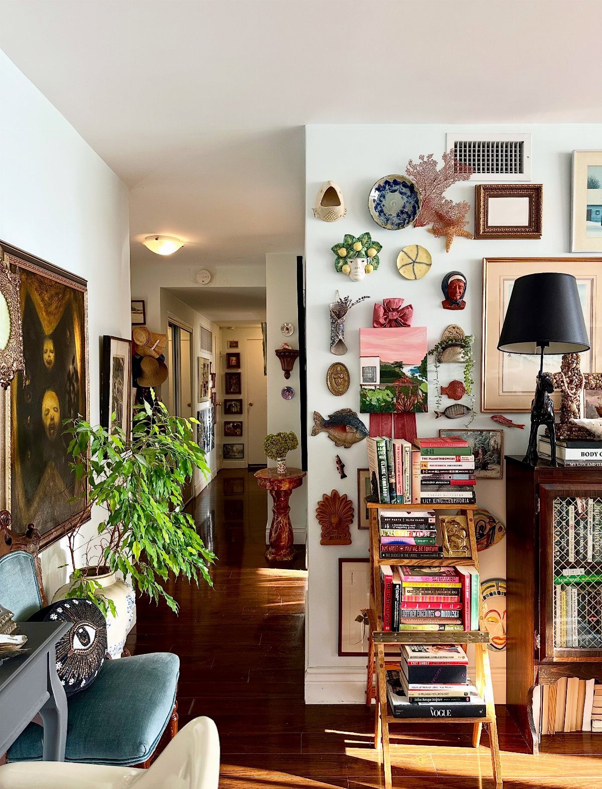 Eclectic hallway interior with a gallery wall of diverse art and a bookshelf.