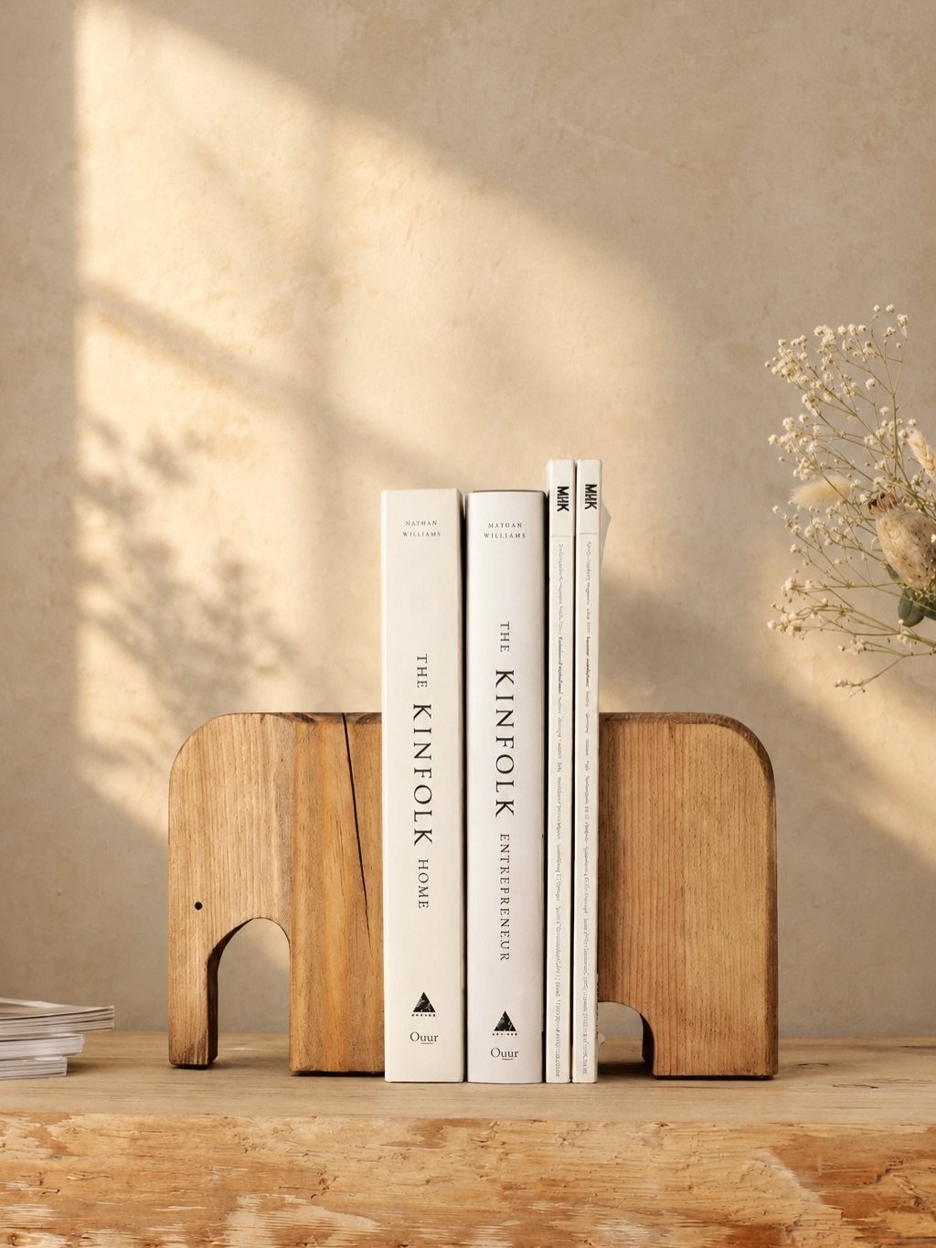 Elephant shaped wooden bookends holding white books on a rustic wooden table