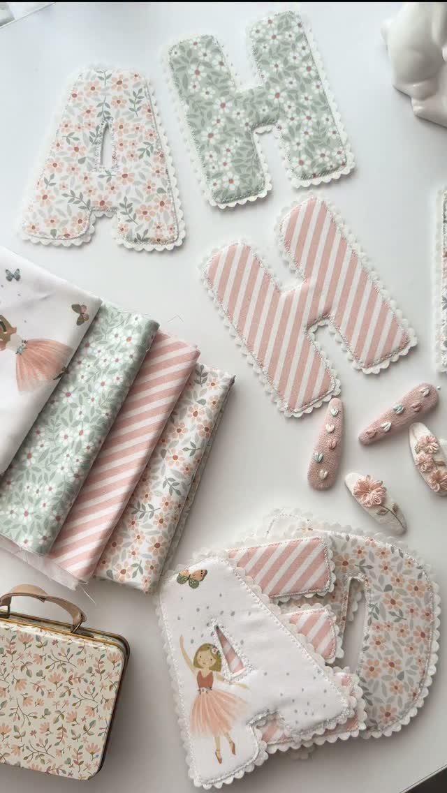 Fabric letters and craft supplies with floral and striped patterns on white background.