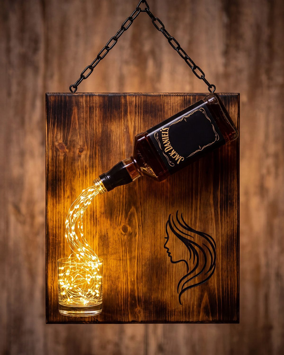 Jack Daniel's bottle mounted on wood with fairy lights pouring into a glass
