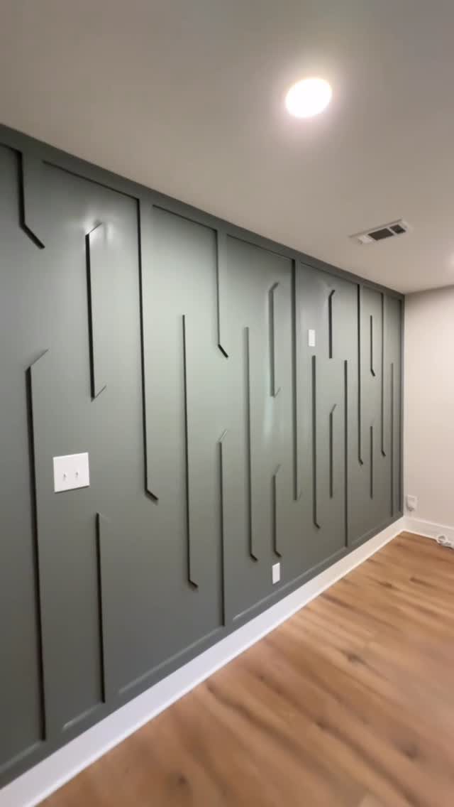 Dark grey accent wall with raised geometric vertical lines and wooden flooring.