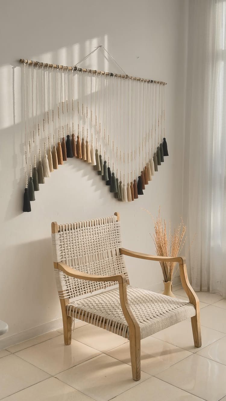 Macrame wall hanging with neutral tones hanging above a woven wooden chair.