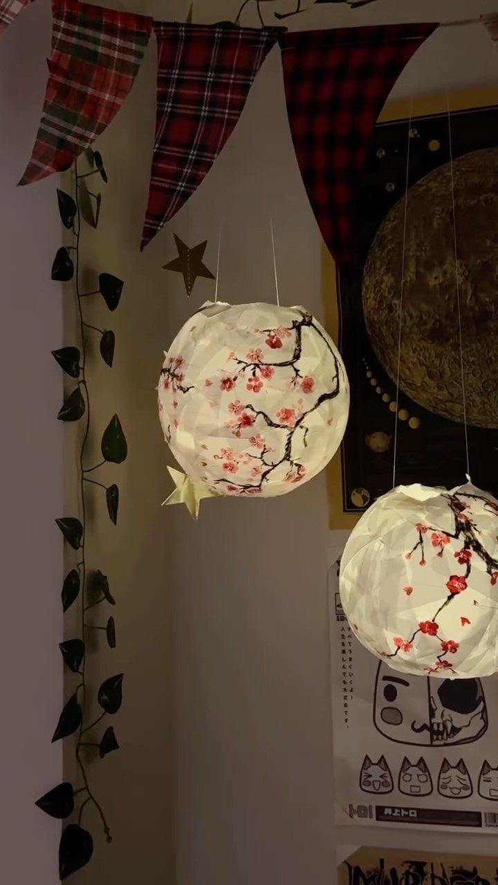 White cherry blossom paper lanterns hanging in a decorated room corner with plaid banners.