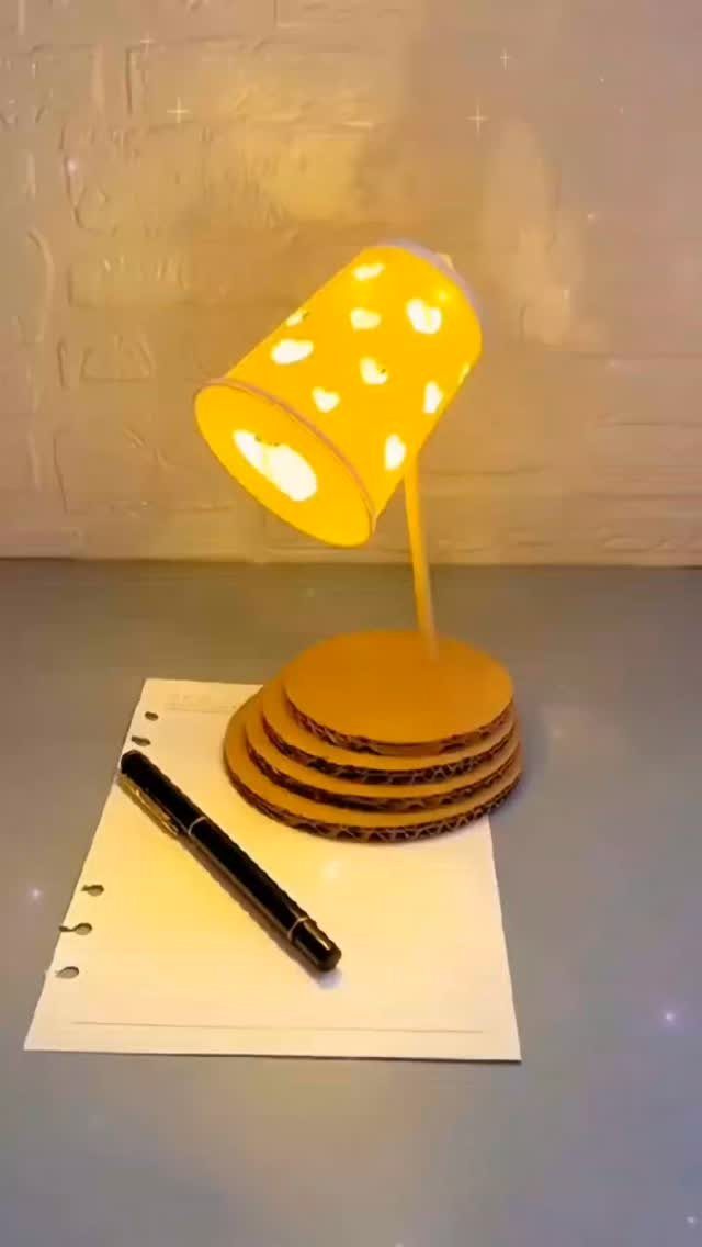 DIY LED Light Lamp Ideas: 27 Backlights, Pendants, Table Lamps 26 Handmade yellow LED lamp with perforated shade on cardboard base next to a notebook.
