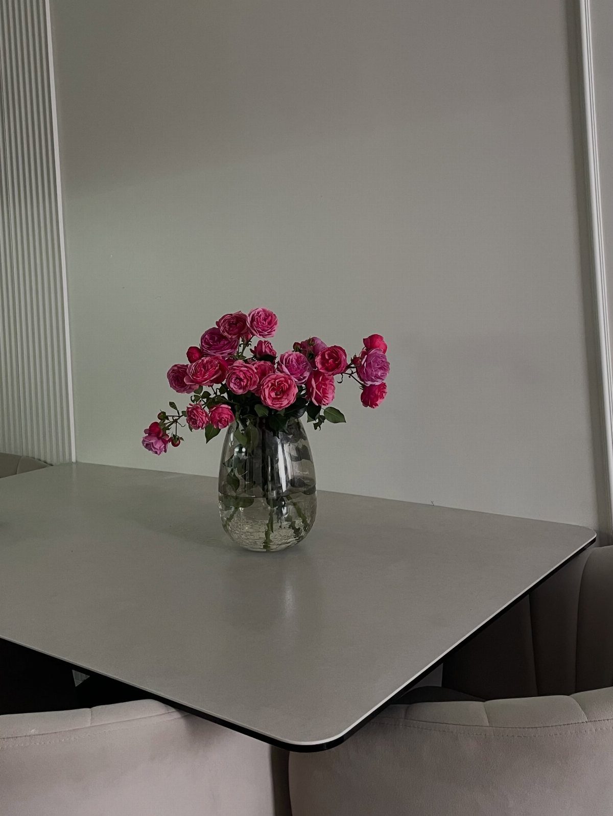 Pink roses in a clear glass vase on a grey table.