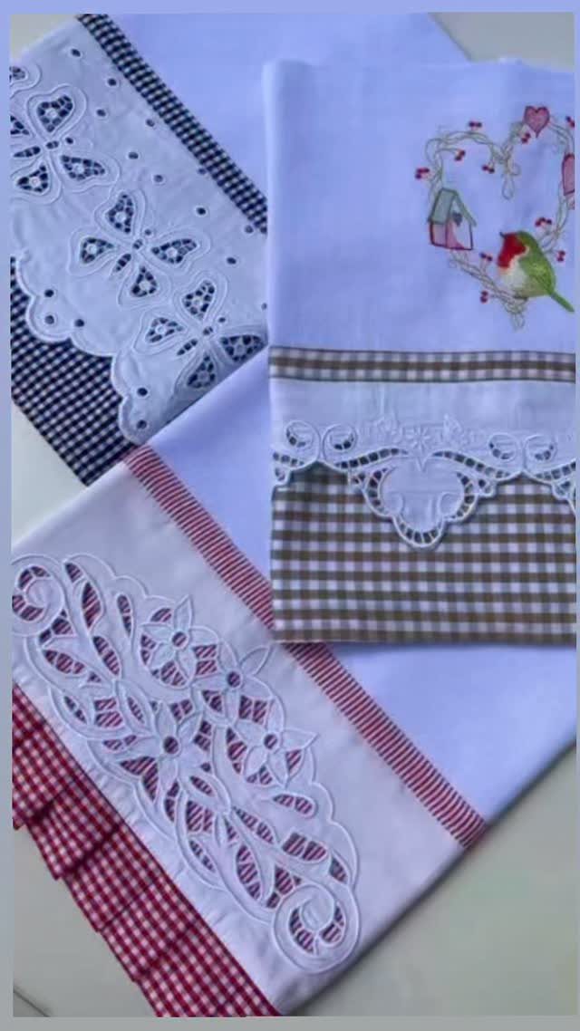 Three white kitchen towels with colorful gingham borders and intricate white lace embroidery.