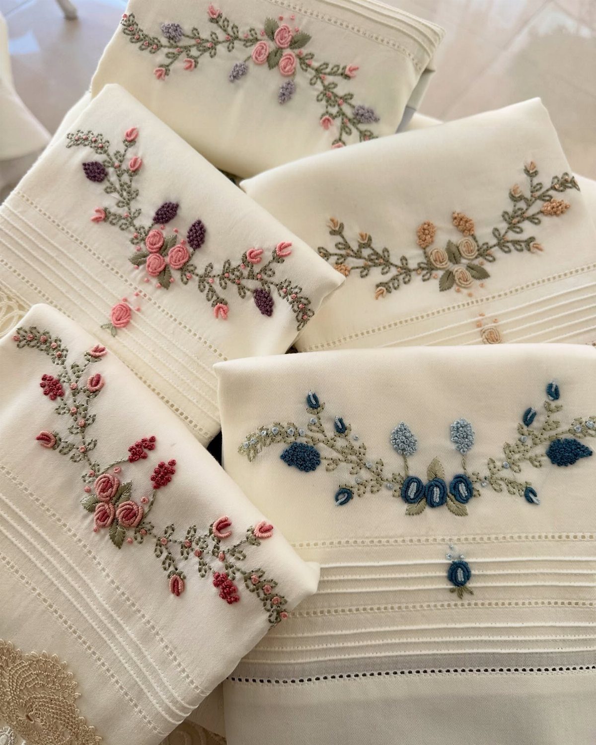 White kitchen towels featuring colorful floral embroidery in pink, blue, and orange tones.