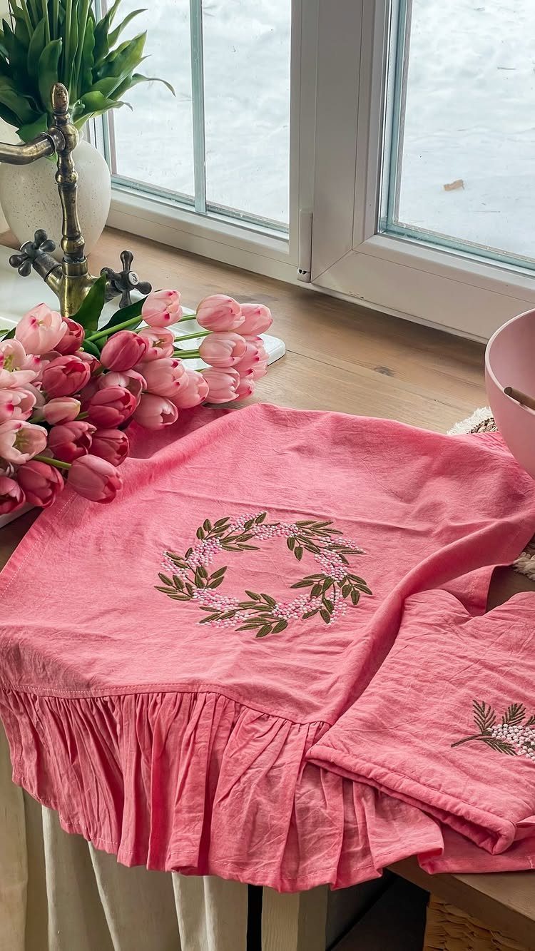 Pink ruffled kitchen towels with an embroidered green leaf wreath and pink tulips.