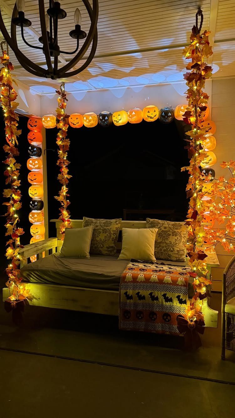 Glowing pumpkin and autumn leaf garlands decorating a cozy outdoor porch swing at night