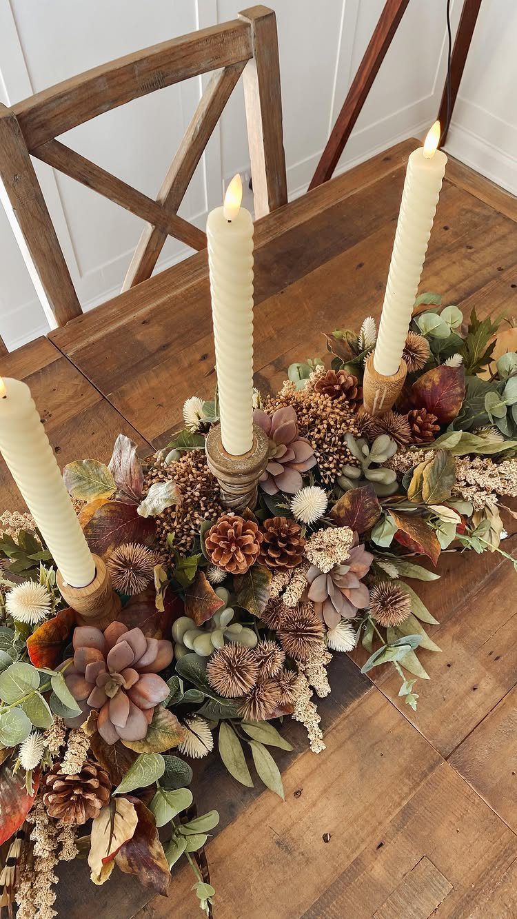 Autumn table runner with faux leaves, pinecones, and three cream taper candles.