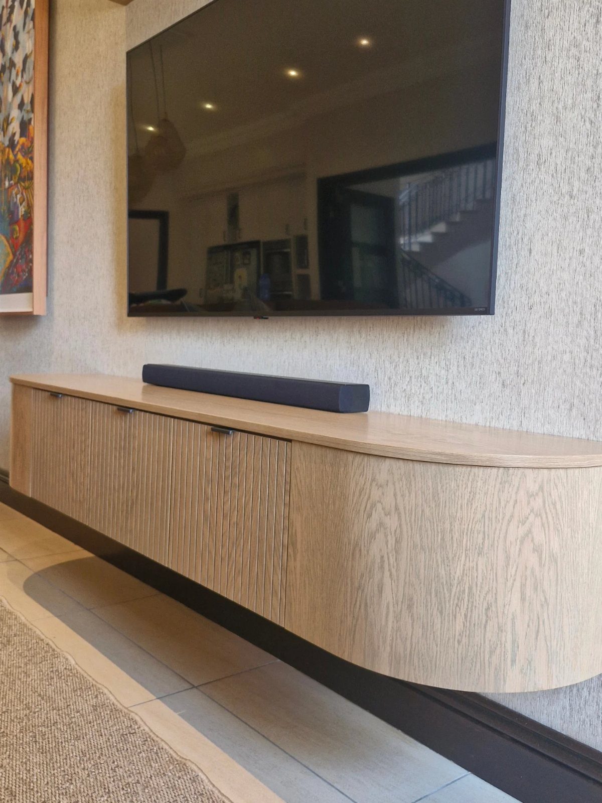 Floating Shelf Under TV Ideas: 31 Styles for Living Rooms 19 Light wood floating shelf with a soundbar mounted under a large wall television