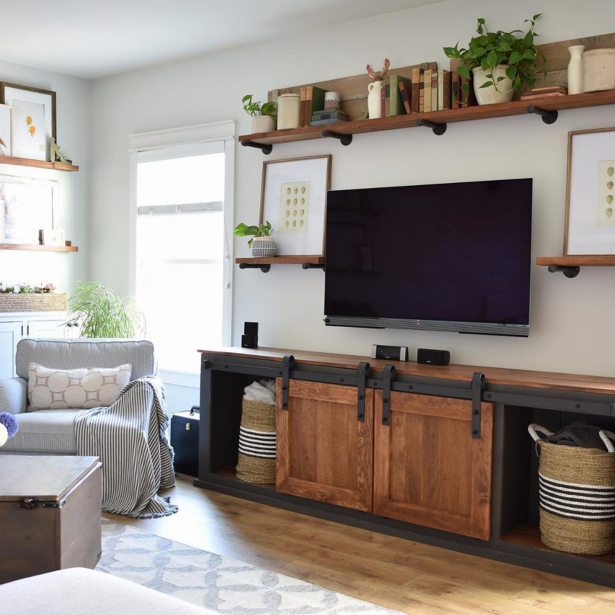 Floating Shelf Under TV Ideas: 31 Styles for Living Rooms 25 Long wooden floating shelf with books and plants mounted above a wall-mounted TV.