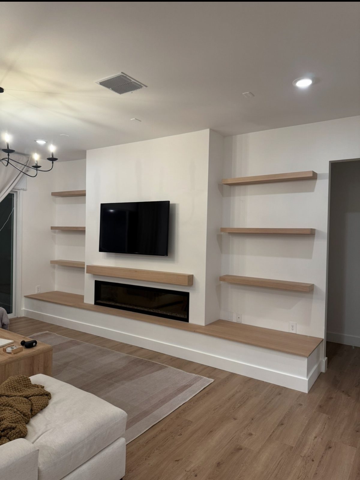 Floating Shelf Under TV Ideas: 31 Styles for Living Rooms 8 Light wood floating shelf under a wall-mounted TV above a modern fireplace.