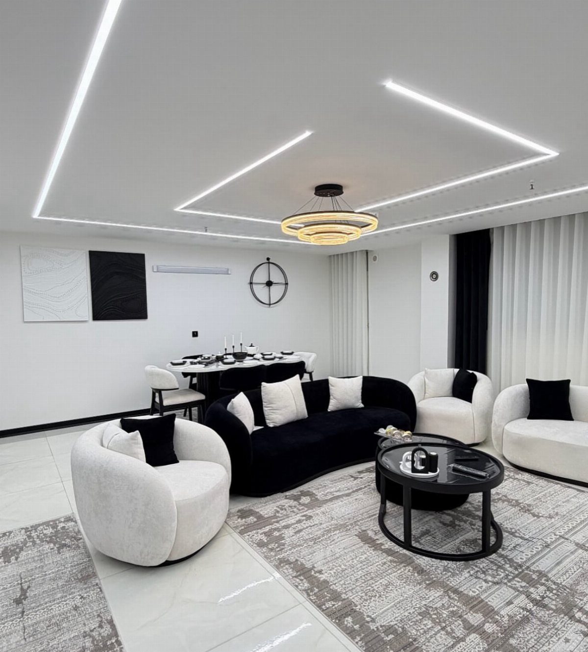 Modern living room with black curved sofa and white armchairs against white walls.