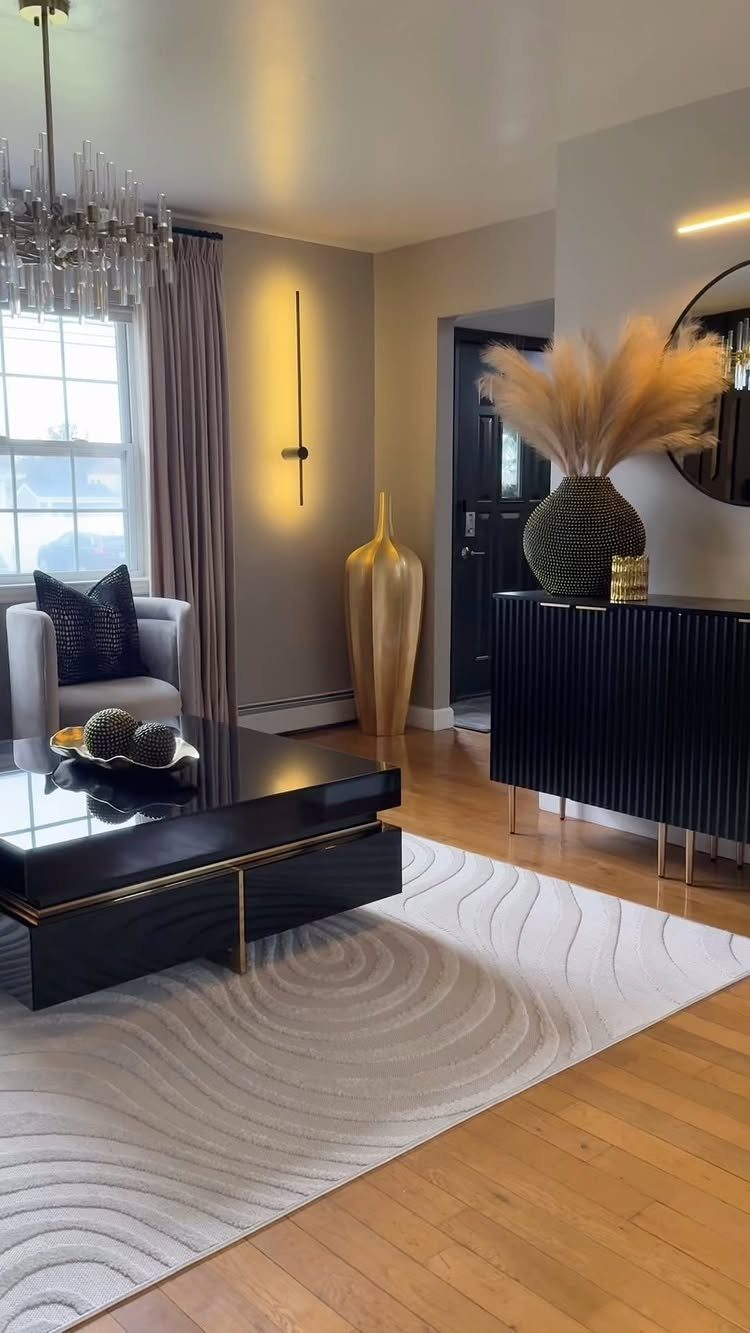 Modern living room with gold accents on furniture, a gold vase, and crystal chandelier.