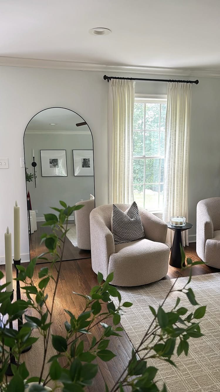 Large arched floor mirror leaning against a wall in a bright living room