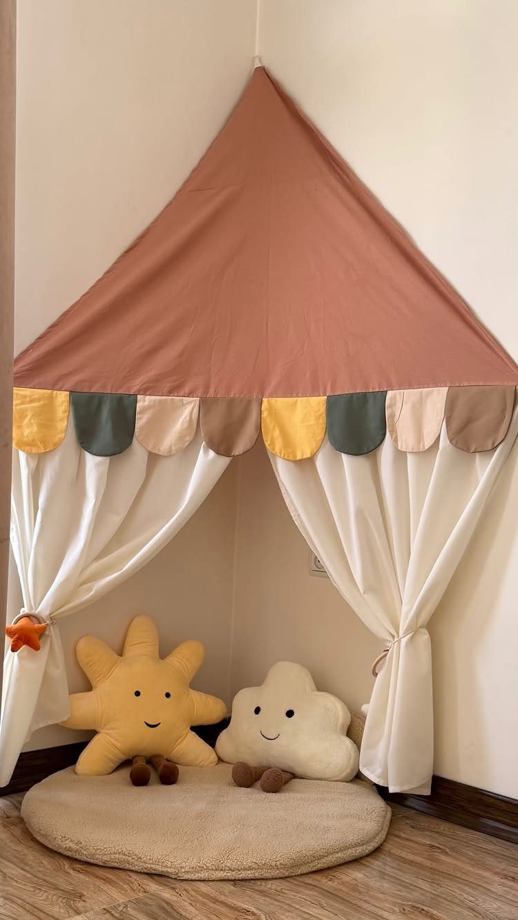 Fabric play tent with plush sun and cloud toys on a round rug.