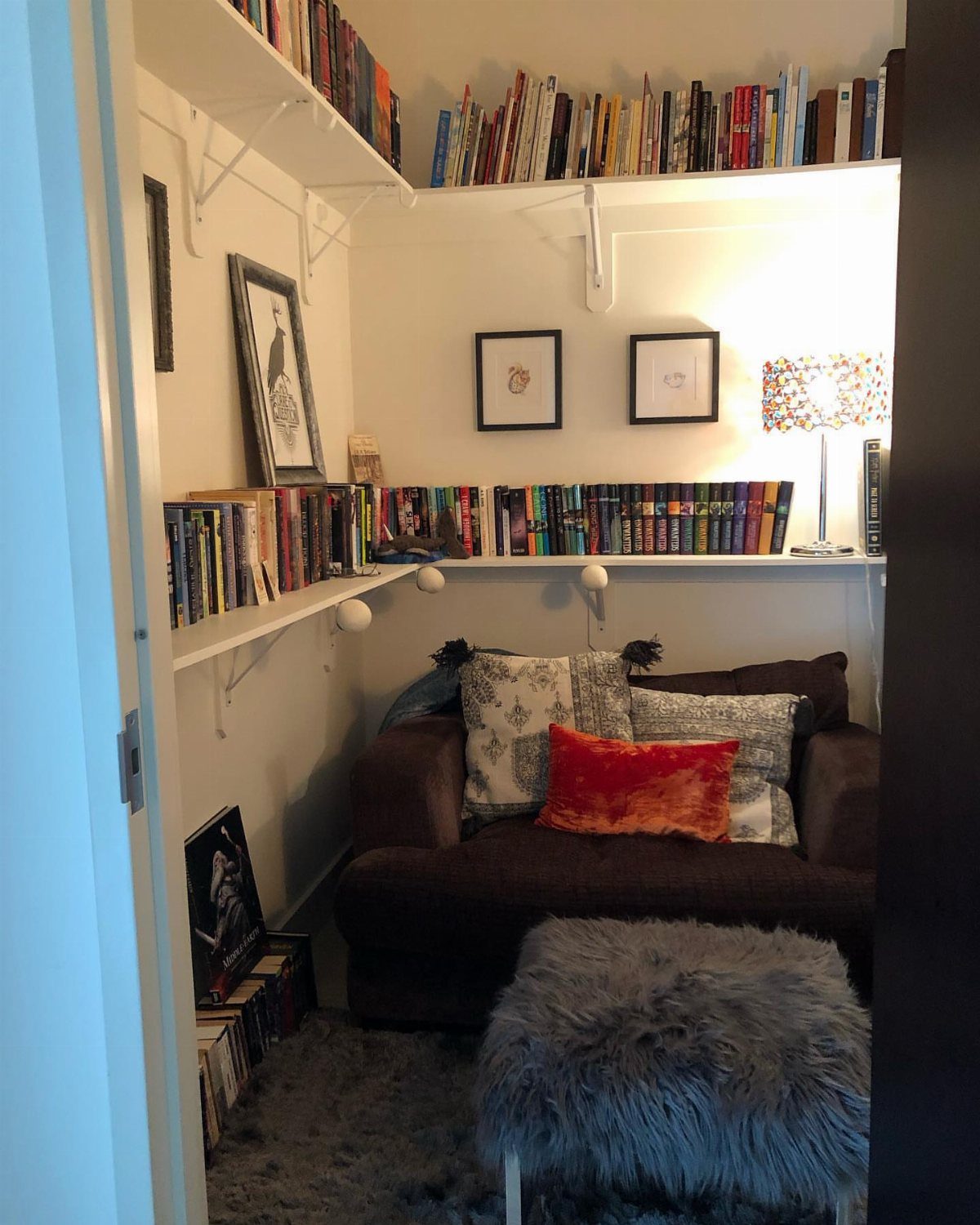 Cozy reading nook inside a closet with a brown armchair and bookshelves.