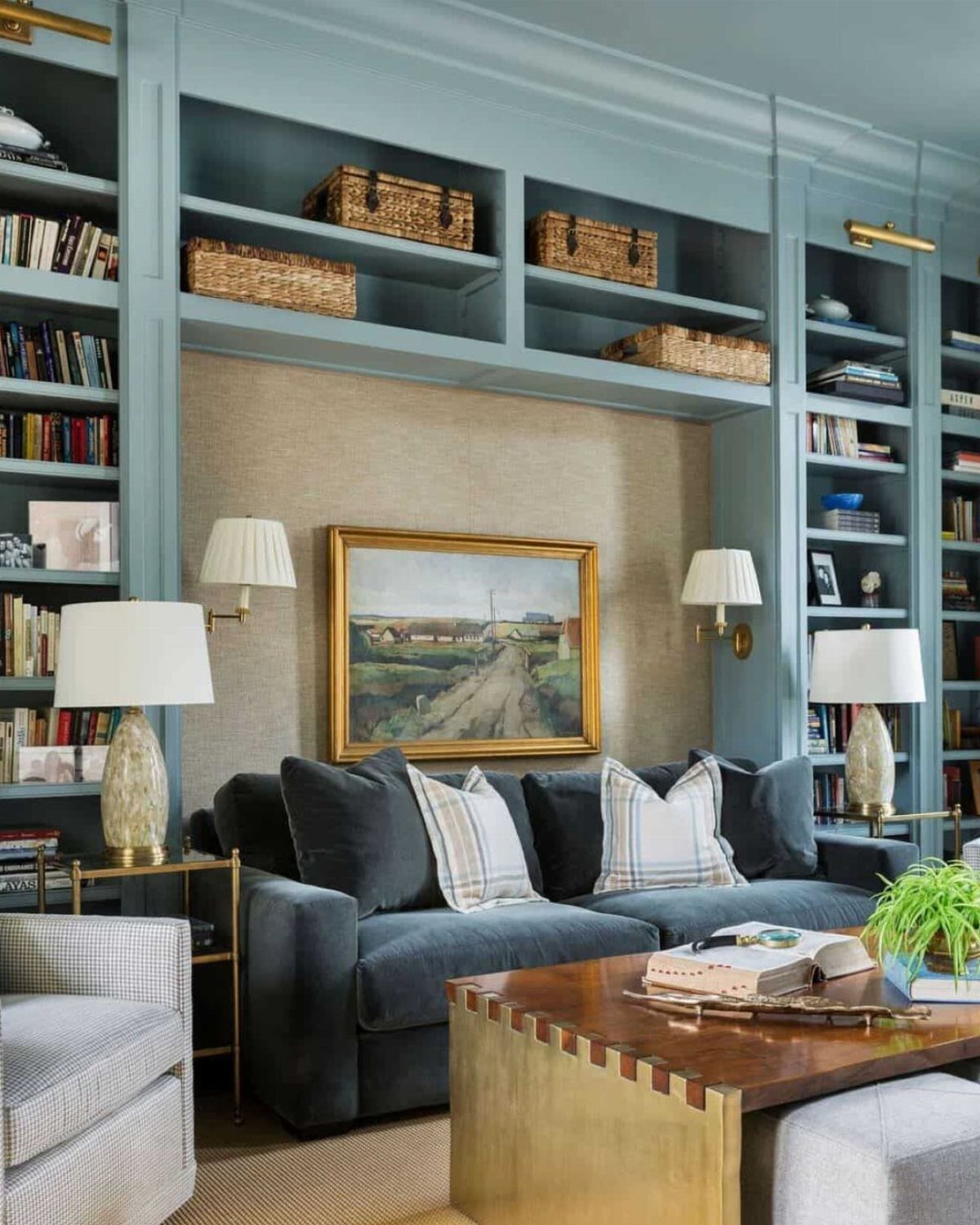 Dark blue velvet sofa in a reading nook surrounded by light blue bookshelves.