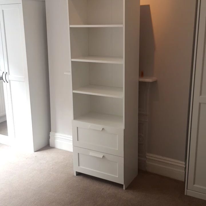 White BILLY bookcase with open shelving and two bottom drawers against a grey wall.