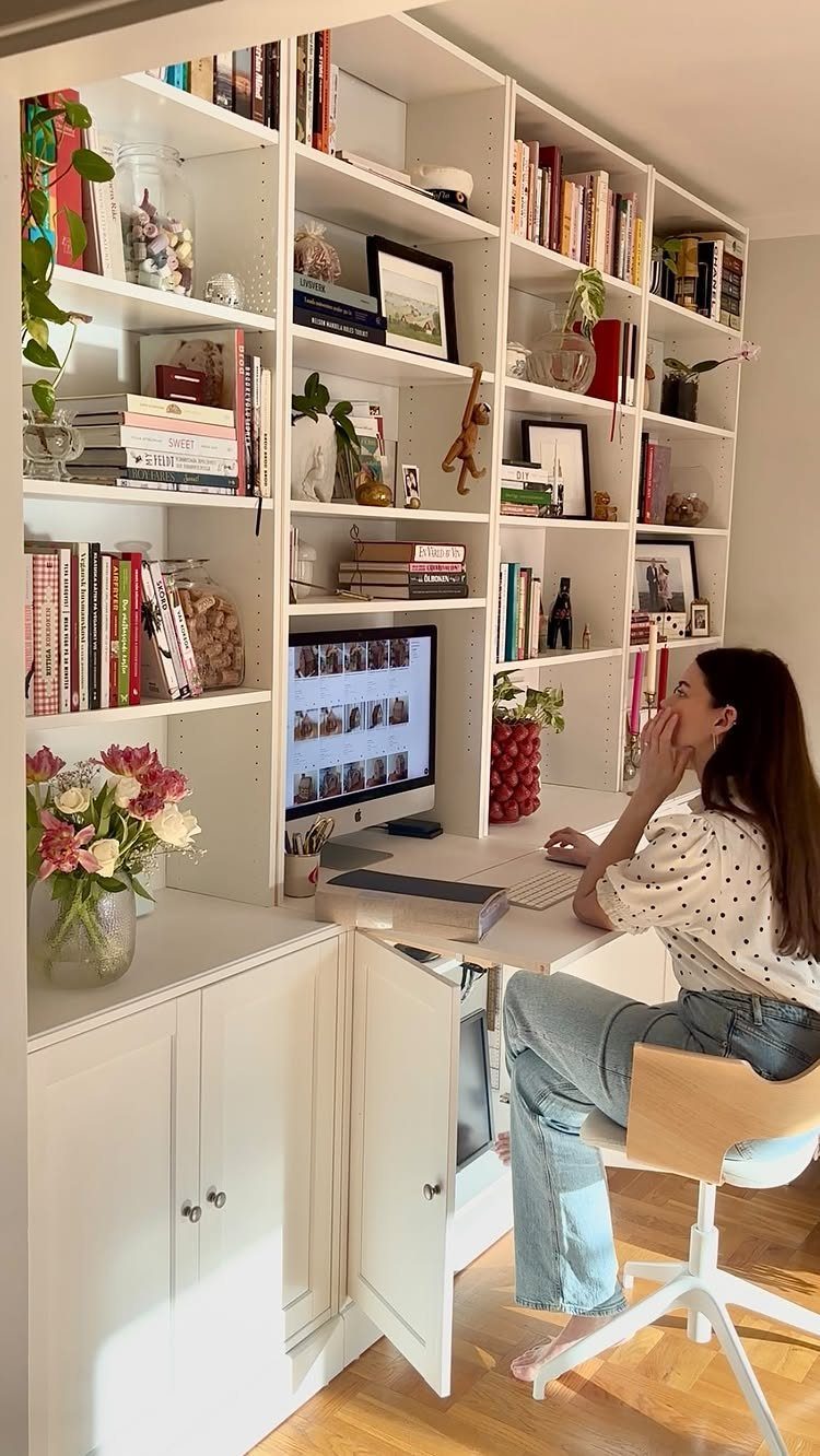 Woman working at a white desk integrated into a large white BILLY bookcase system.