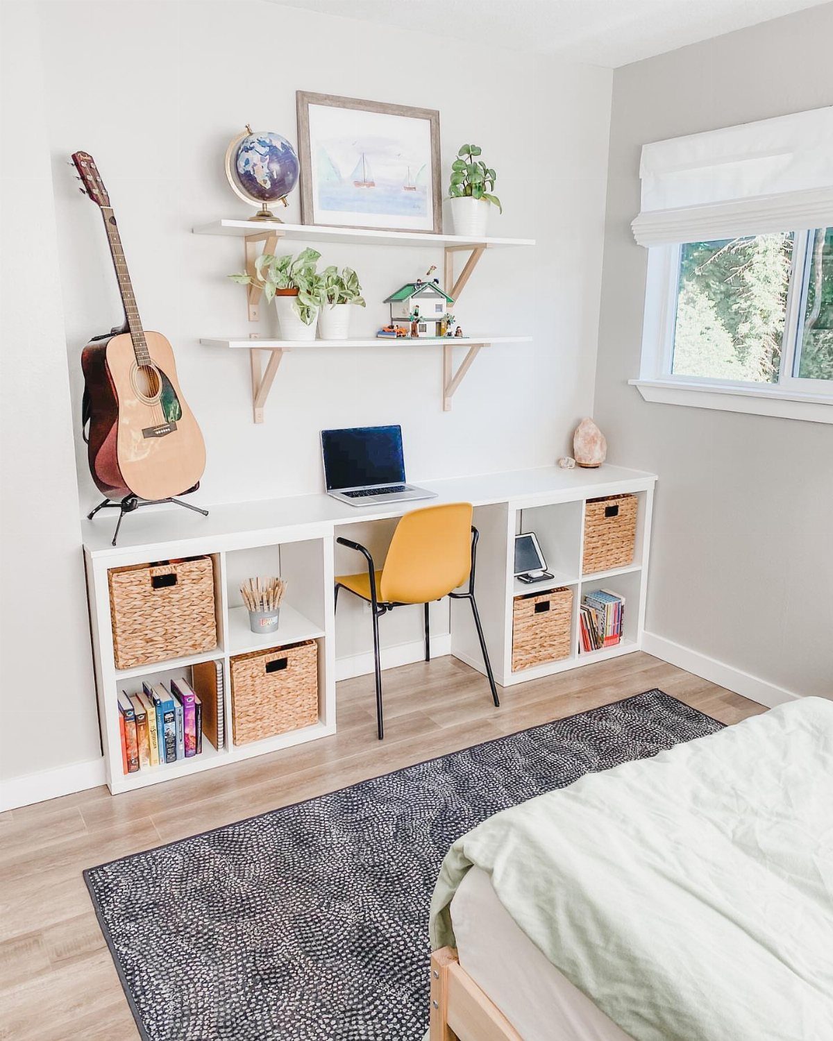 White desk supported by KALLAX cube units with a yellow chair and laptop.