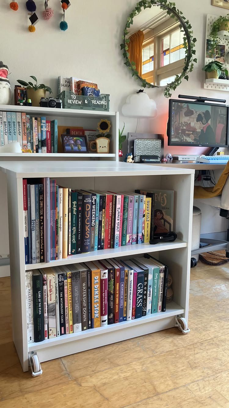 White rolling bookcase filled with books in a home office with a computer desk.