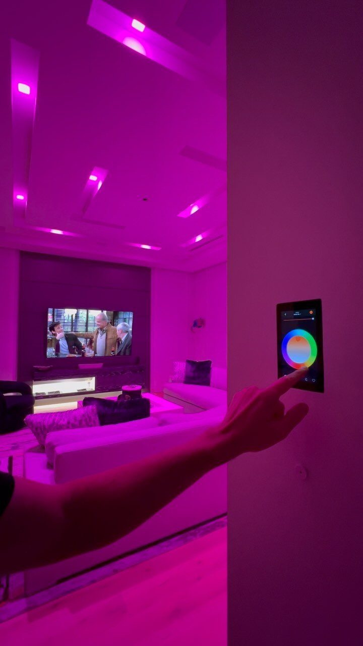 Hand adjusting a color wheel on a wall panel for purple cove lighting.