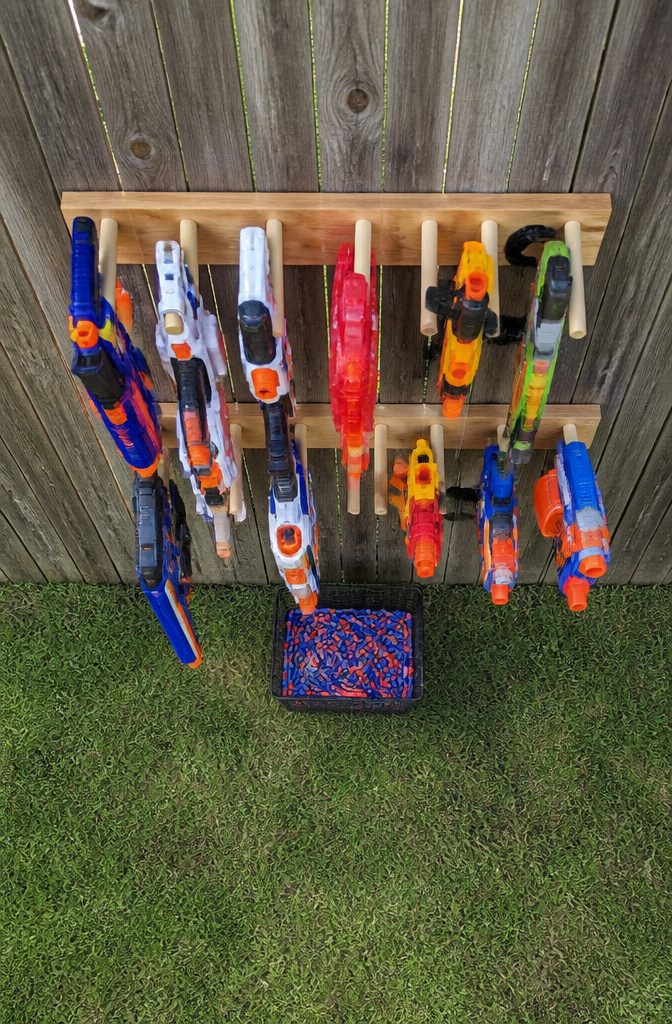 13 Kids Outdoor Toy Storage Ideas to Organize Every Yard (2026) 5 Wooden rack holding Nerf guns and magazines on a fence.