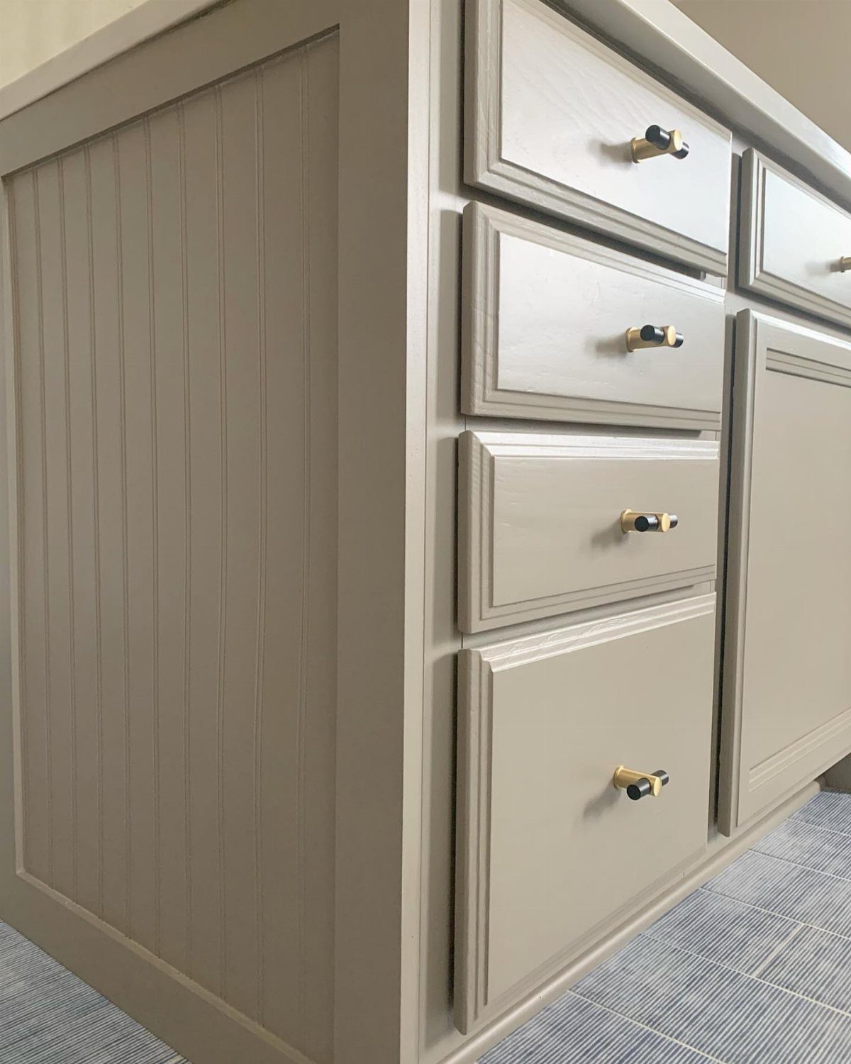 13 Kitchen Island Back Panel Ideas, From Beadboard to Stone 2 Grey kitchen island with beadboard paneling on the back and gold drawer knobs.