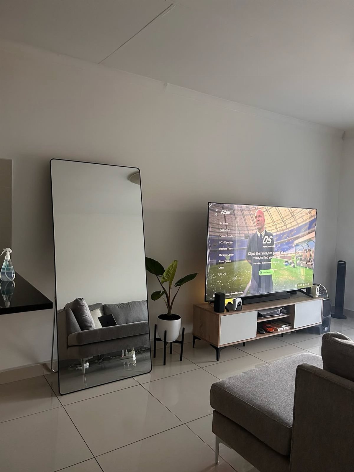 Large rectangular floor mirror leaning against a white wall in a modern living room.