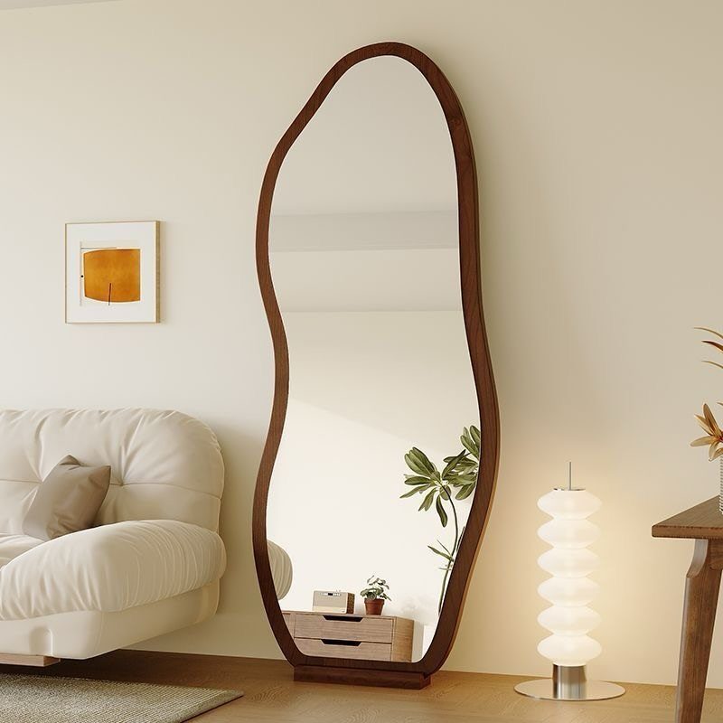 Large organic shaped floor mirror with wooden frame in a modern white living room