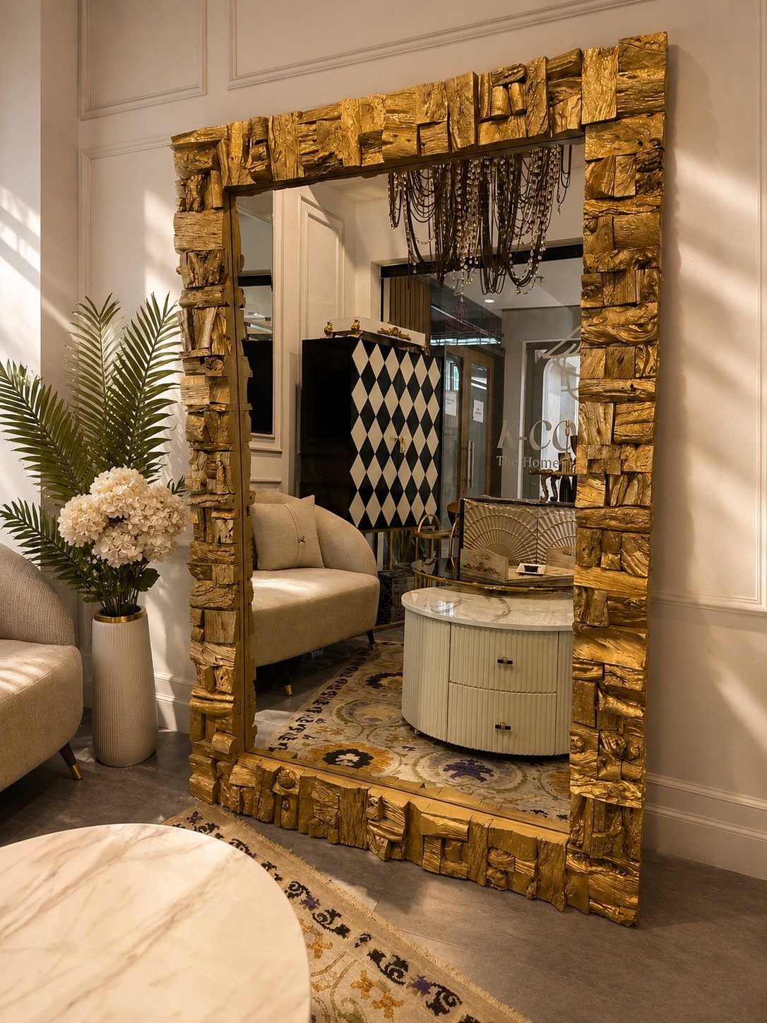 Large rectangular floor mirror with a thick gold ornate frame in a living room.