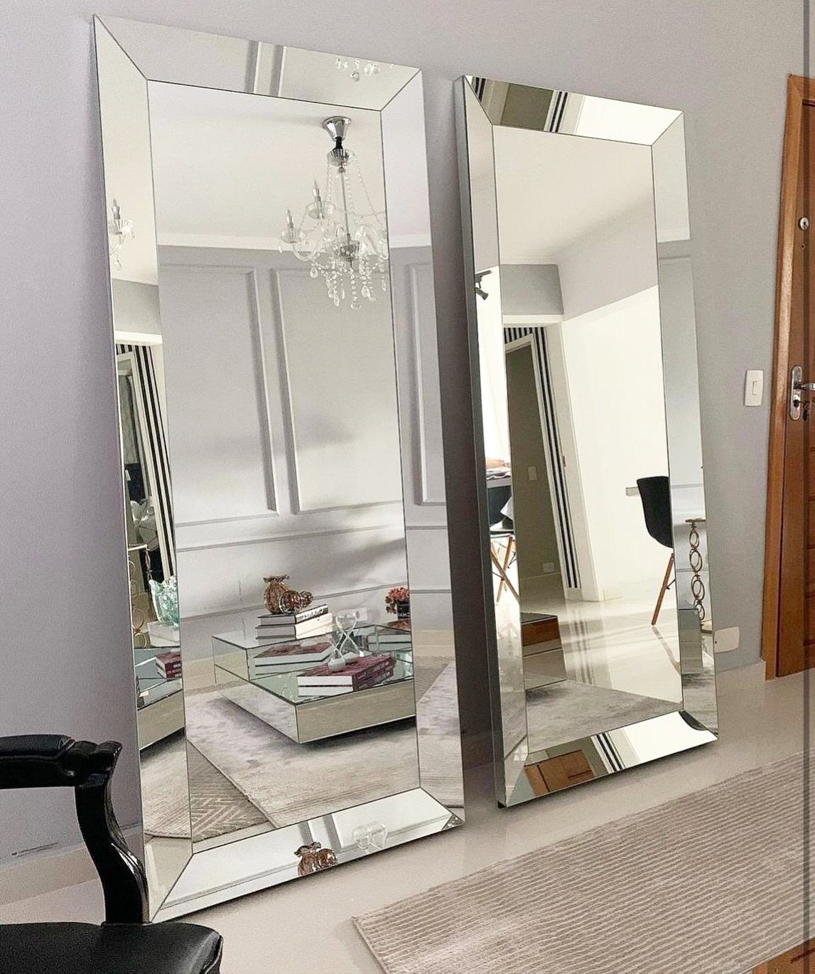 Two large beveled floor mirrors leaning against a wall in a modern living room.