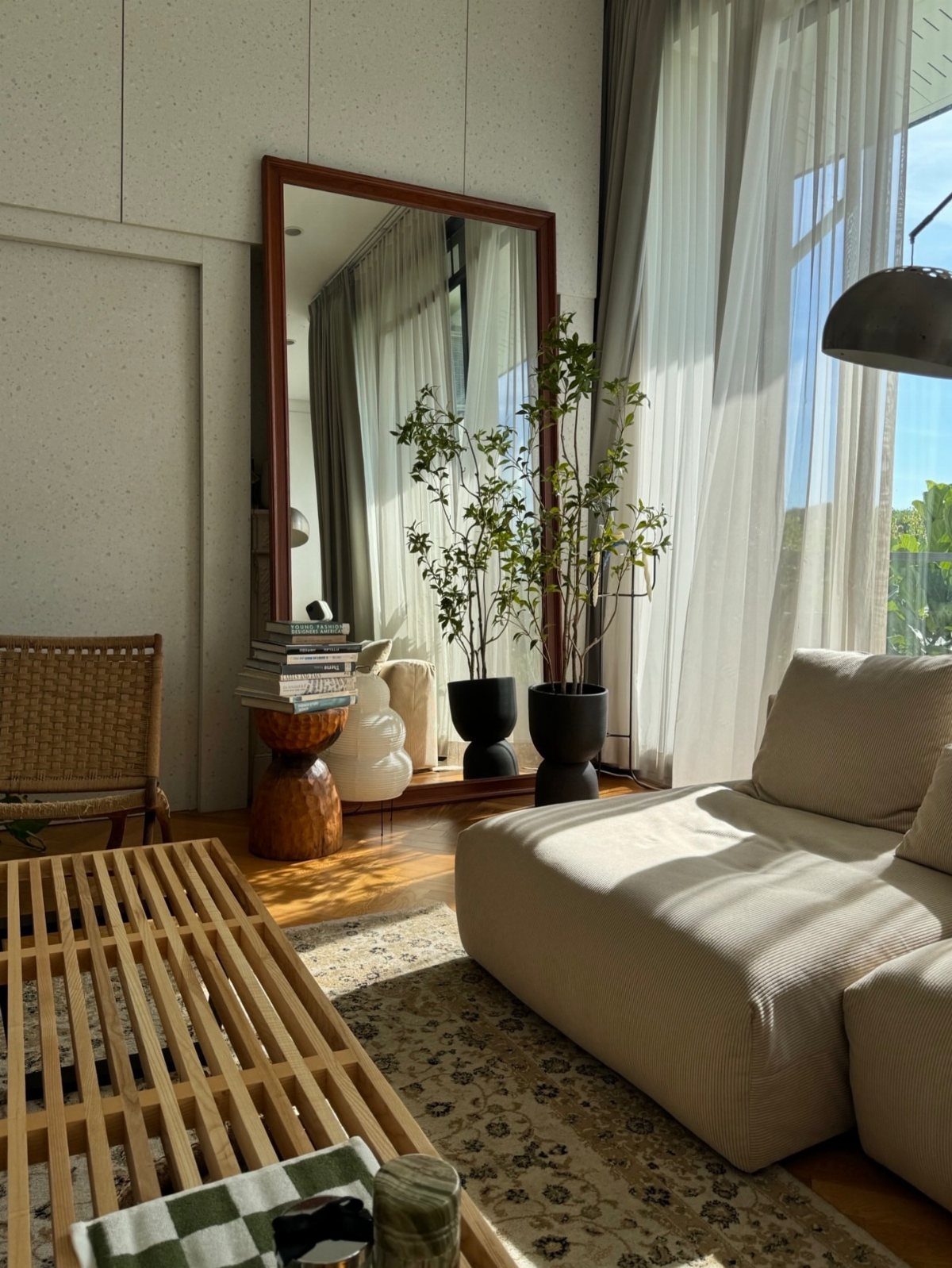 Large rectangular floor mirror leaning against a white wall in a sunlit living room.