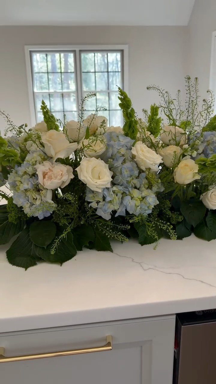 Large Floral Centerpieces: 5 Ideas for Tables and Seasons 3 Large floral centerpiece with white roses and blue hydrangeas on a white marble counter.