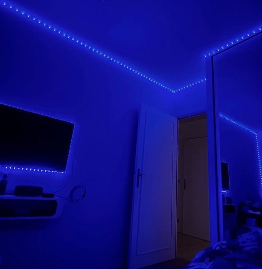 Lights for Room Decoration: 12 Ideas for Every Style in 2026 9 Blue LED strip lights lining the ceiling and television in a bedroom