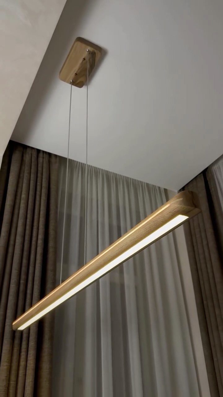 Lights for Room Decoration: 12 Ideas for Every Style in 2026 4 Linear suspension light fixture with wooden finish hanging from a white ceiling.