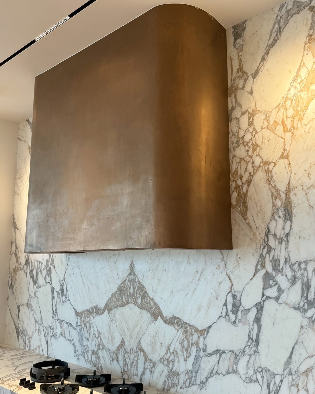 Modern Kitchen Hood Ideas: 12 Designs from Metal to Minimalist 4 Custom bronze metal range hood mounted on a white marbled stone kitchen wall