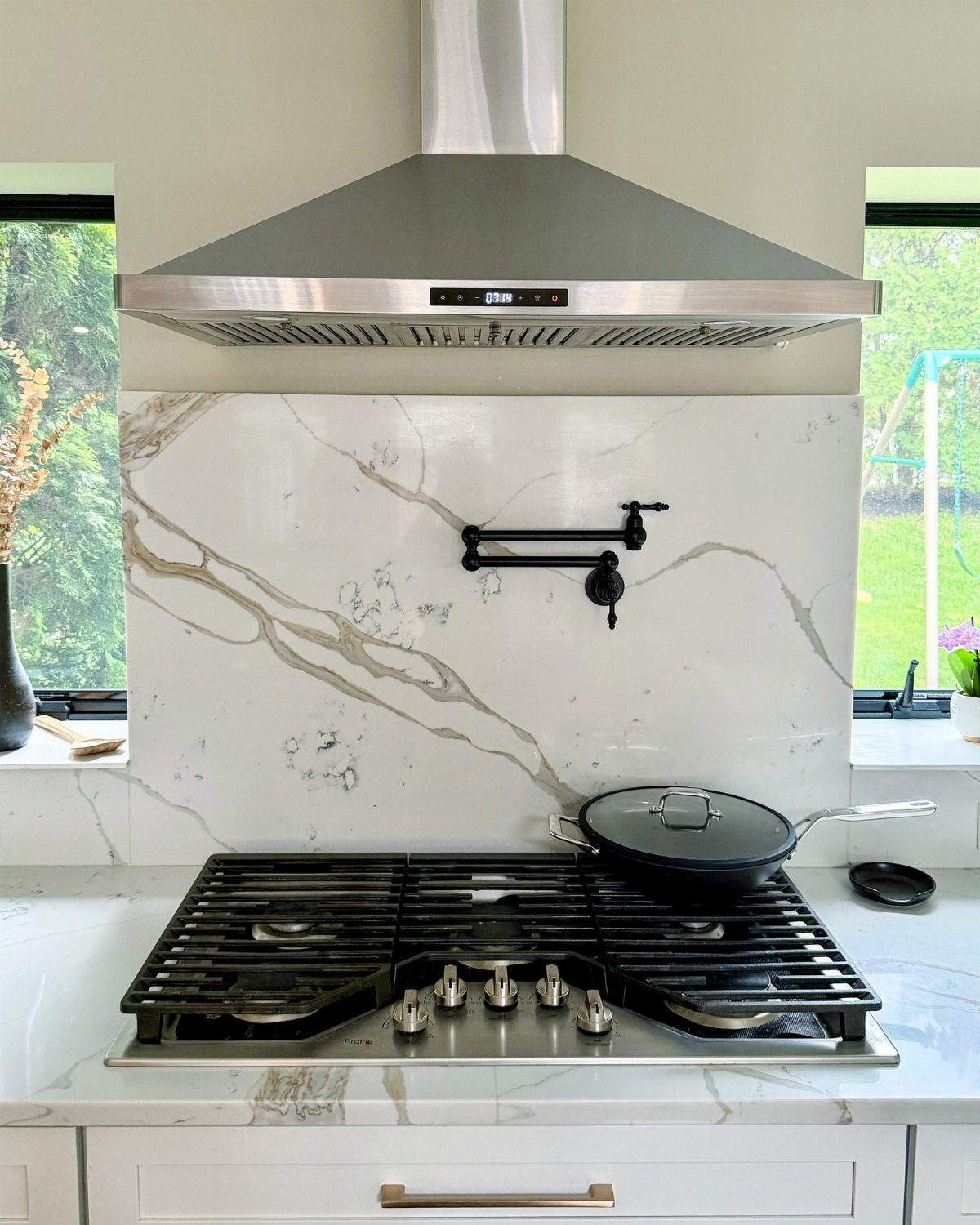 Modern Kitchen Hood Ideas: 12 Designs from Metal to Minimalist 12 Stainless steel range hood above a gas stove with white marble backsplash