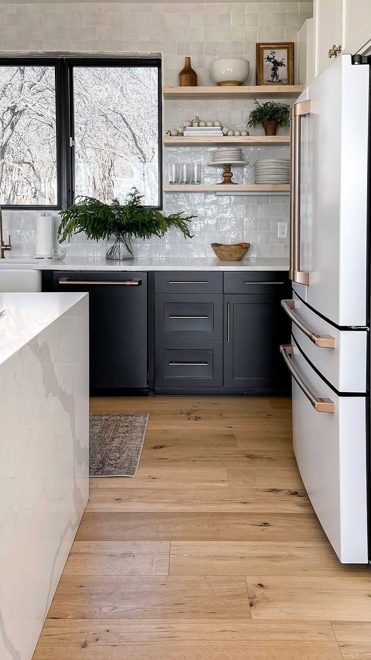 Wooden floating shelves with ceramics and plants above dark grey kitchen cabinets.