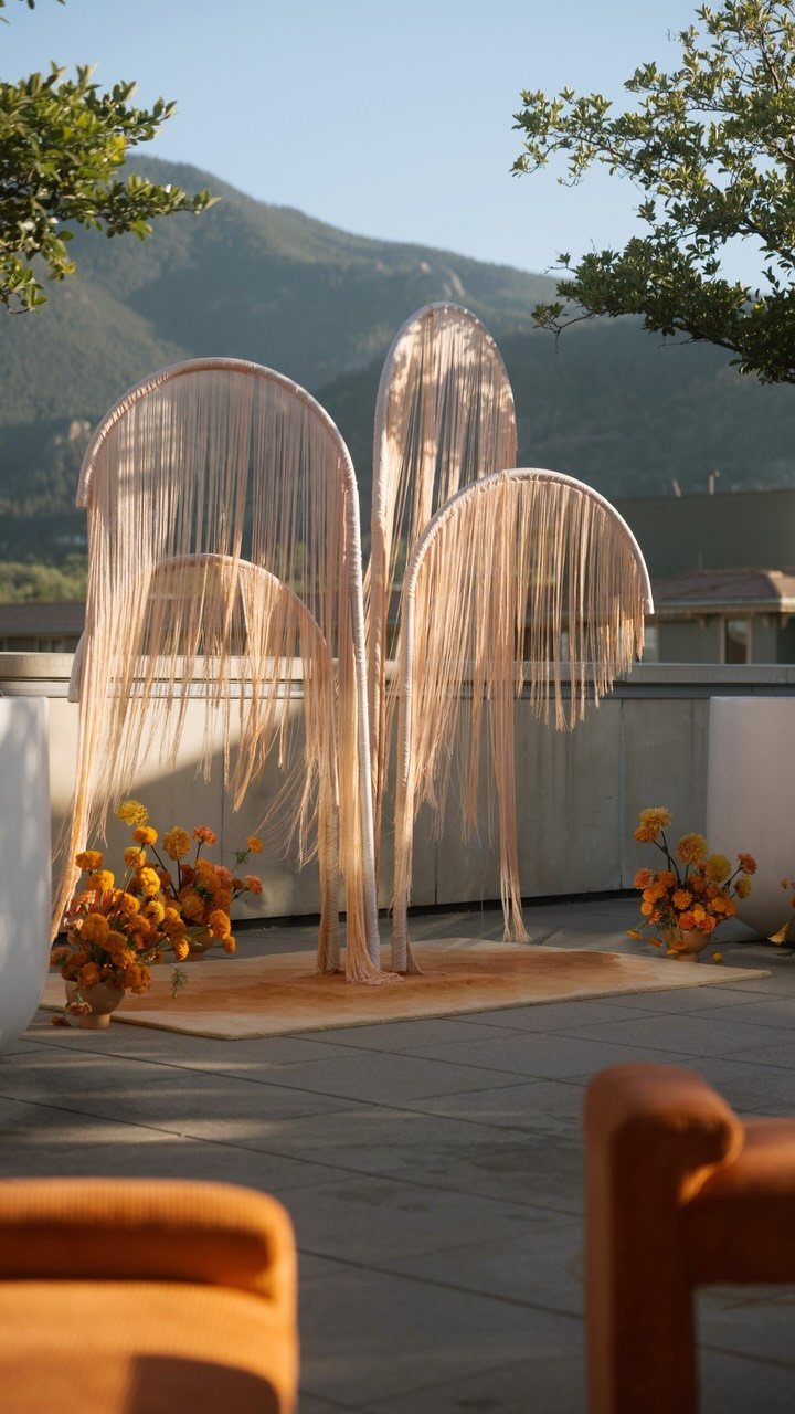 Beige fringe arched backdrops with orange flowers on a rooftop terrace with mountains